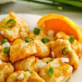 Air fryer orange chicken plated with oranges and green onions