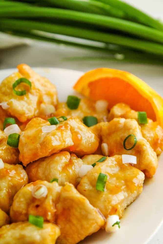 Air fryer orange chicken plated with oranges and green onions