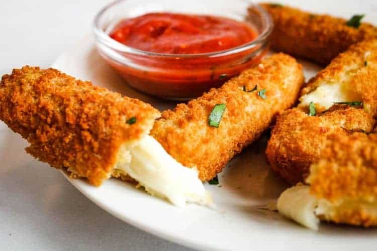 Mozzarella Stick broken in half with melted cheese coming out on a white plate