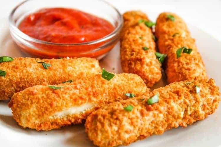 Mozzarella Sticks Served on a white plate with marinara in bowl