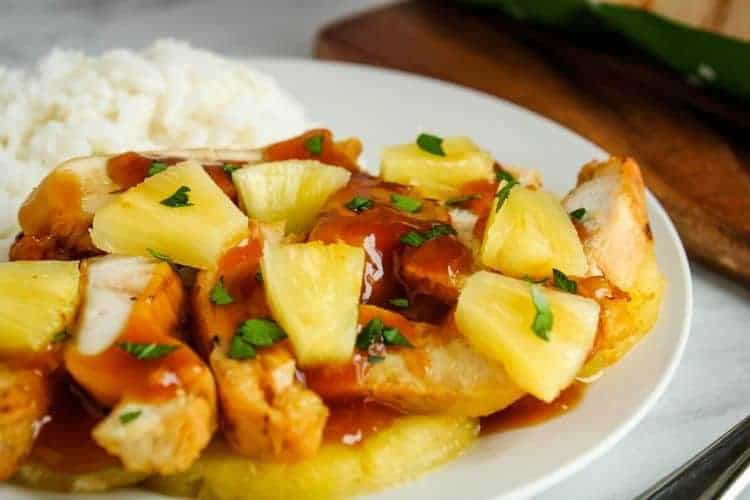 Chicken with Pineapple Sauce and Pineapple Chunks with rice on a white plate