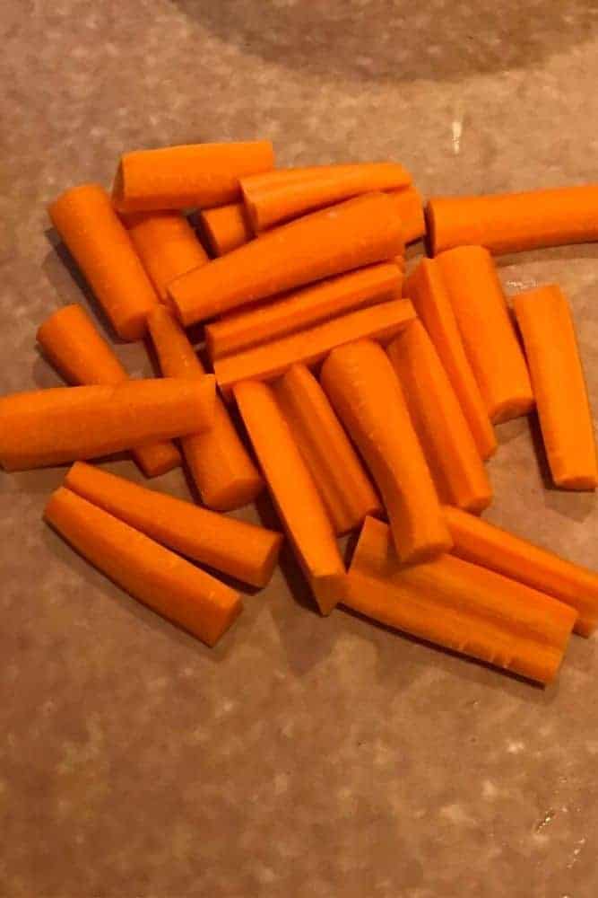 Raw Carrots cut into sticks on cutting board