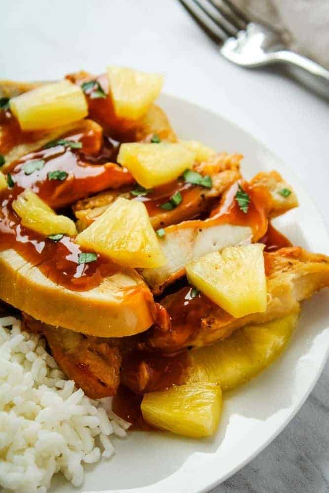 Pineapple Chicken with Pineapple Chunks and rice on a white plate