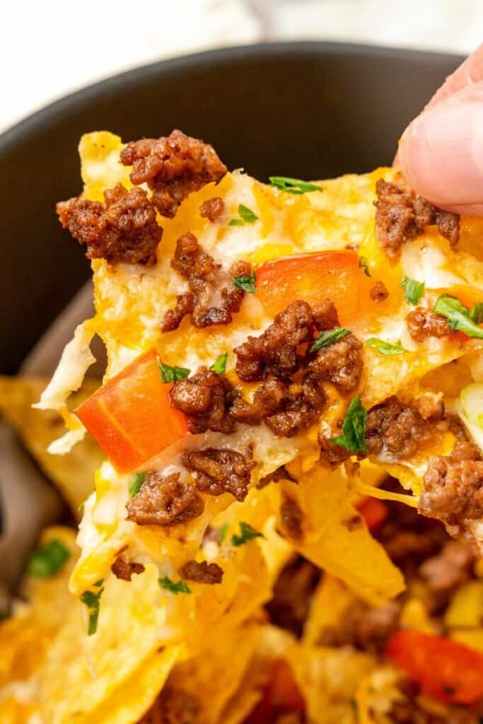 Closeup of chip being pulled from loaded nachos