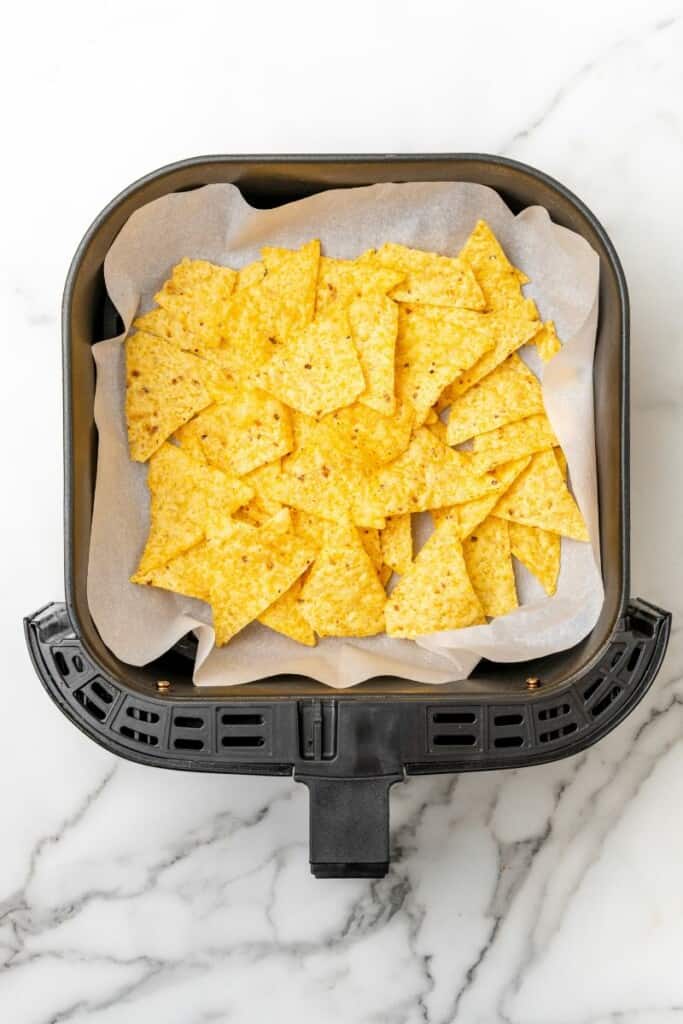 Torrtillas in air fryer basket with parchment paper underneath