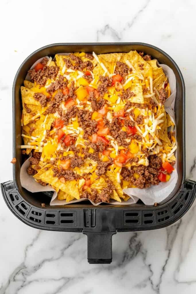 Nachos in air fryer basket before being cooked