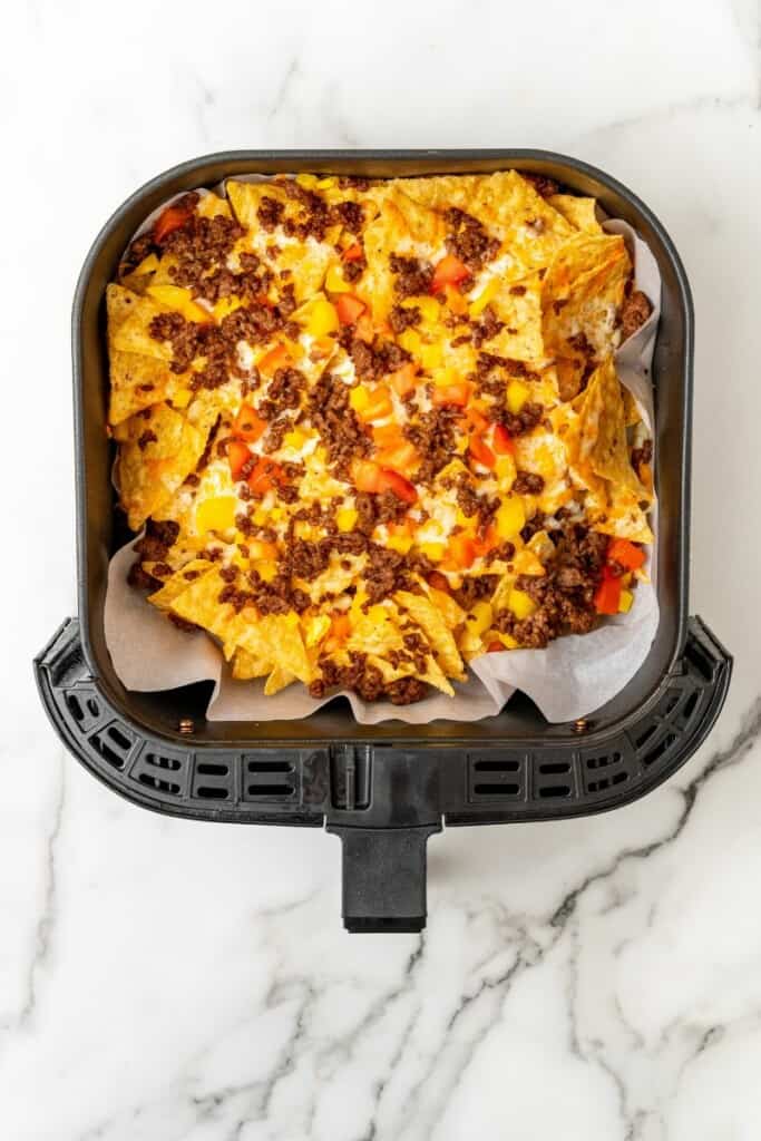 Nachos in air fryer basket before being cooked