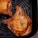 close up of cooked pork chops in an air fryer basket