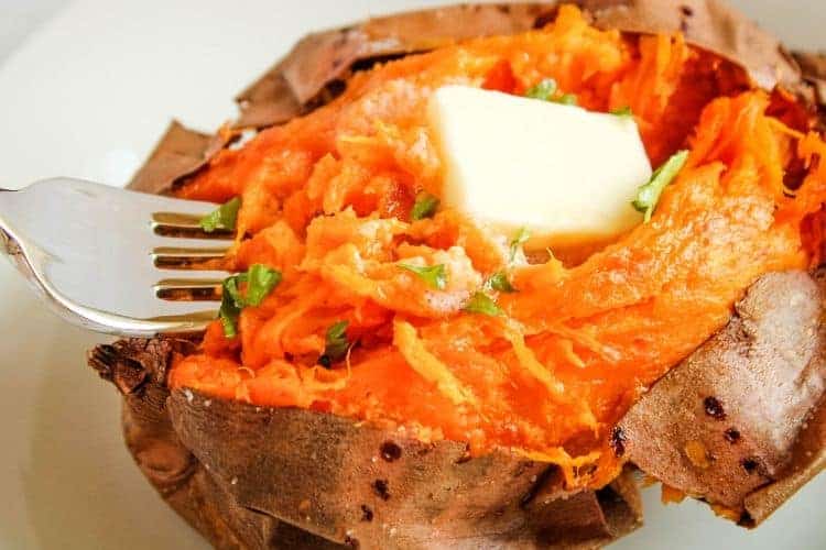 Air Fryer Baked Sweet Potato cut open and fluffed with butter and fork in the middle of it