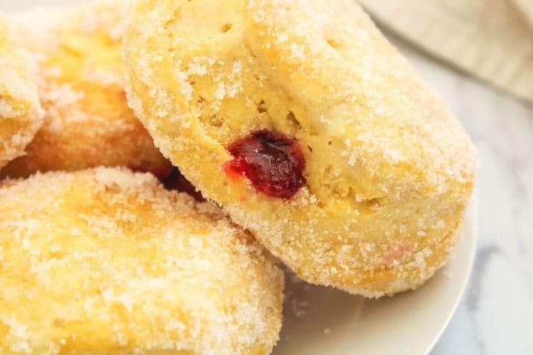 Jelly Donuts on a white plate stacked to the side