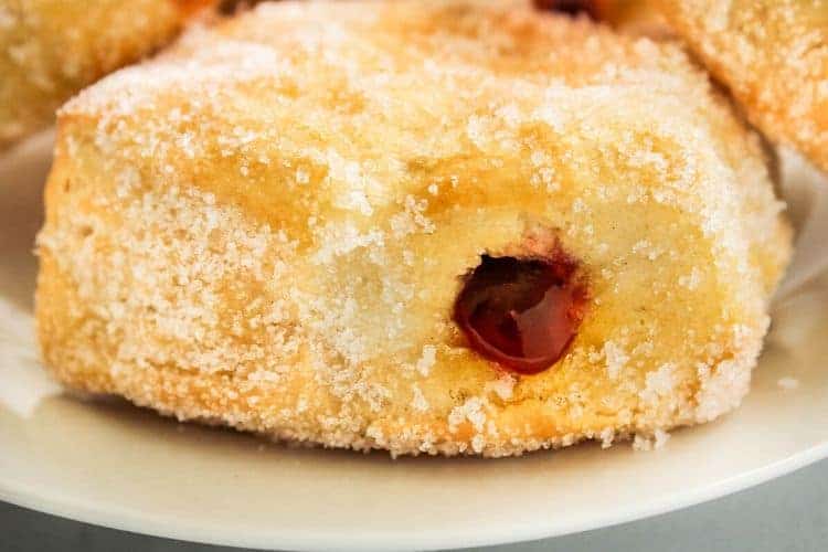 Air Fryer Donuts with jelly showing drizzling out (on a white plate)