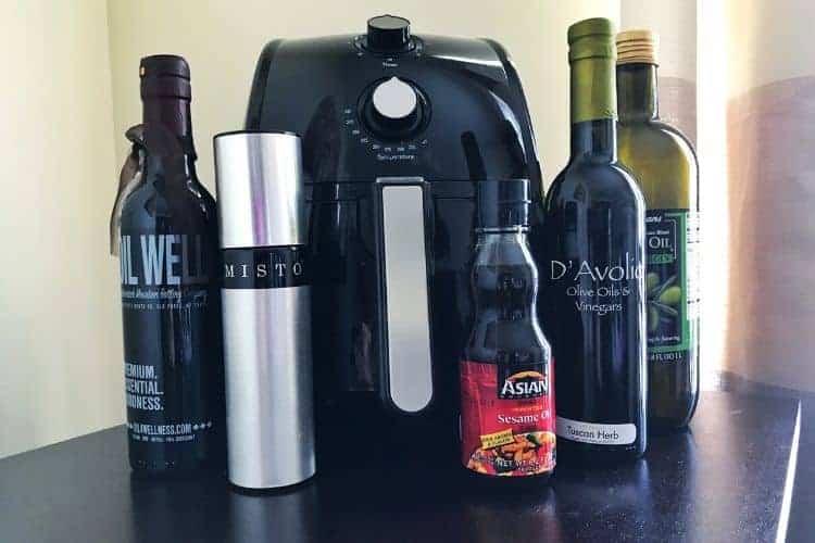 Various oil containers in front of an air fryer.