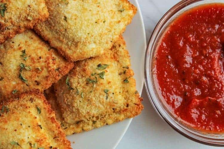 Air Fried Ravioli on a white plate and marinara sauce in a bowl on the right