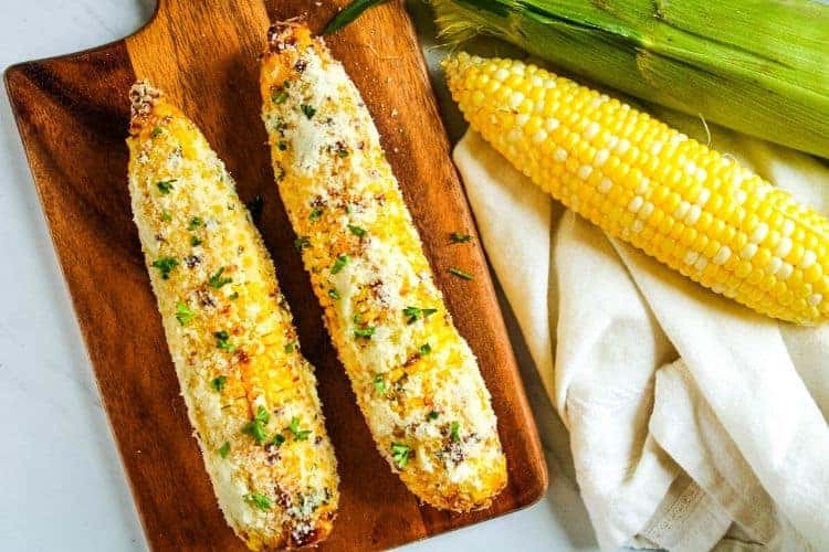 Air Fryer Corn on the Cob rolled in parmesan on a cutting board