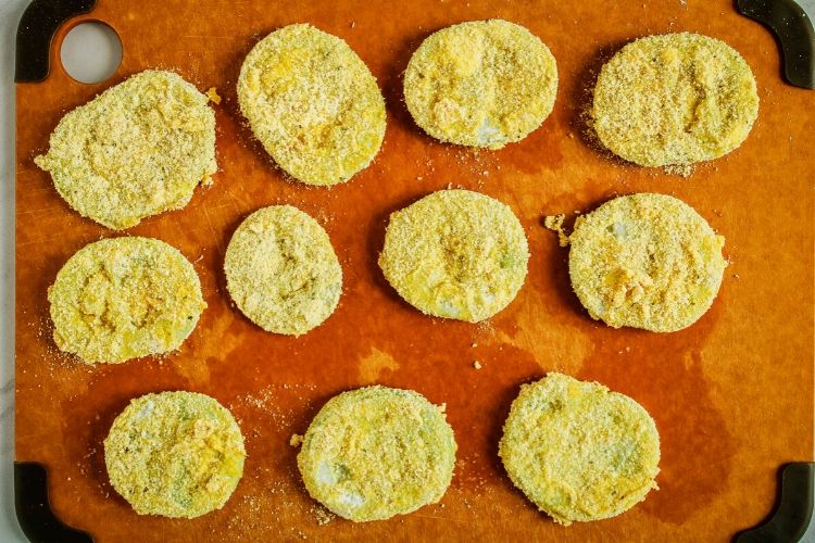 Breaded green tomato slices on cutting board