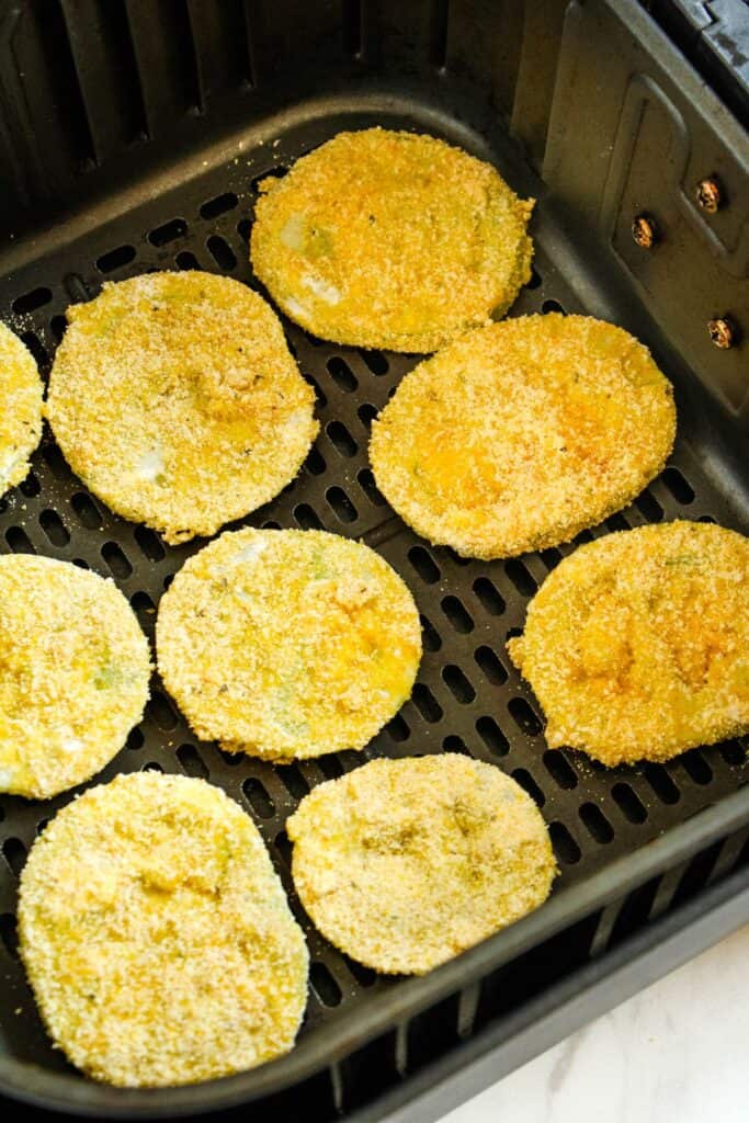 Green tomatoes in the air fryer about to be air fried.