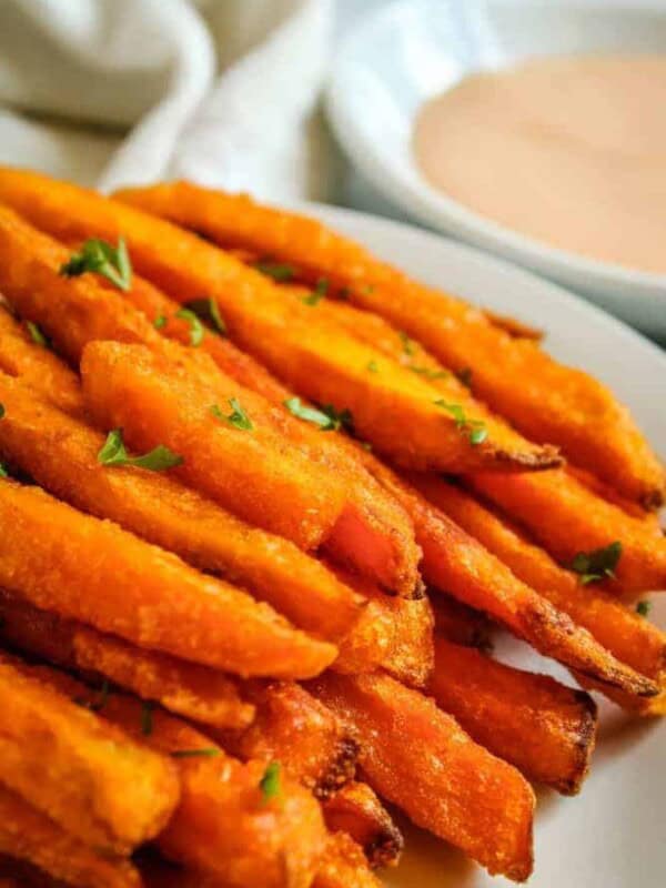 Air Fryer Sweet Potato Fries on white plate with bowl of sriracha mayo in background