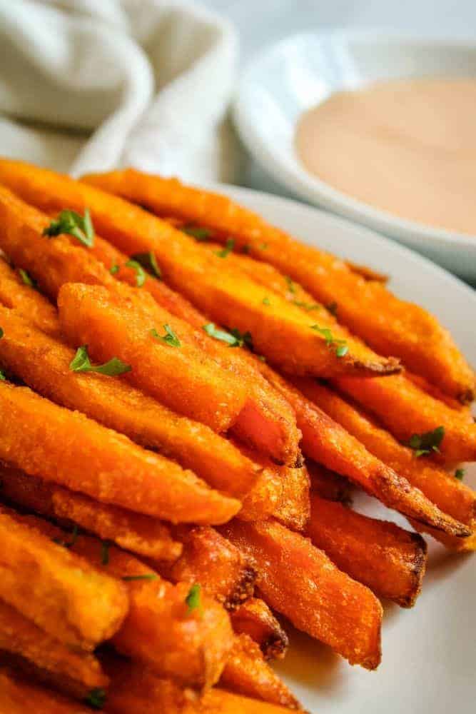 Air Fryer Sweet Potato Fries on white plate with bowl of sriracha mayo in background