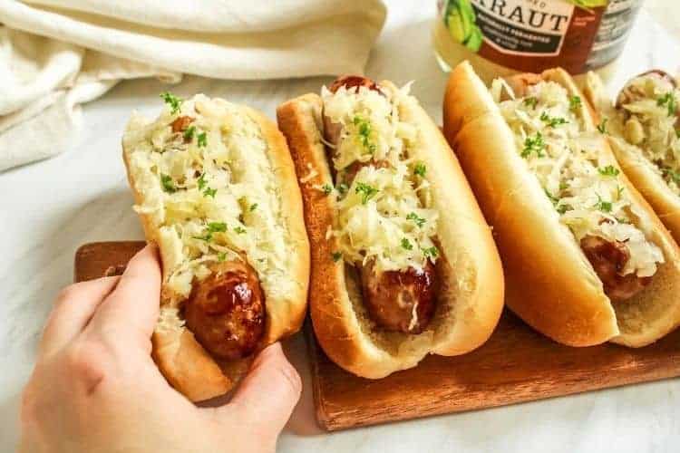 Air fryer snot in buns with sauerkraut on top and grabbing one by hand