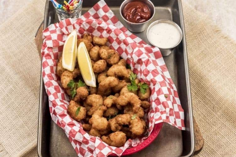 Air Fryer Popcorn Shrimp in a red basket with lemon wedges