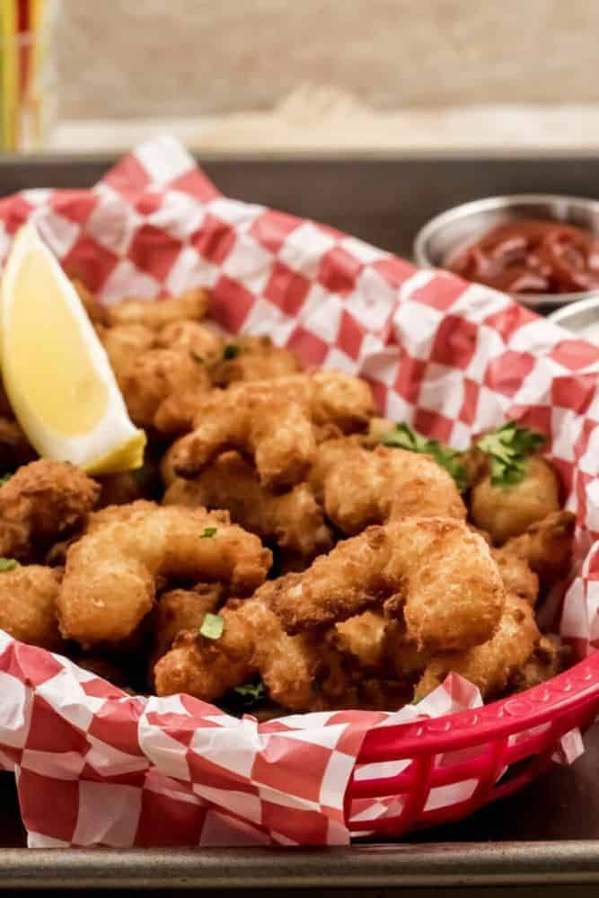 Air Fryer Popcorn Shrimp in a red basket with lemon wedges