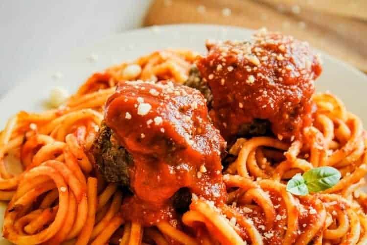 Air Fryer spaghetti and meatballs covered in sauce with basil piece on side