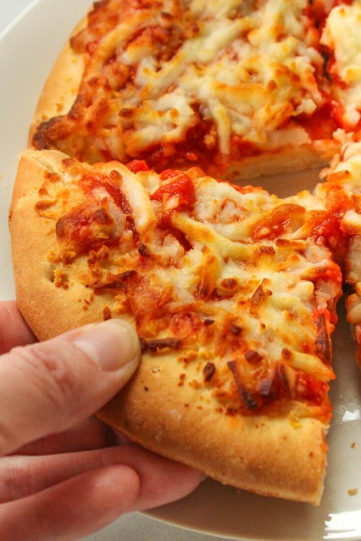 Air fryer pizza slice being held in hand