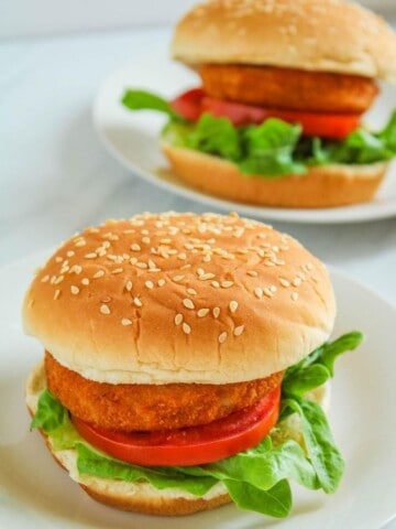Two air fryer chicken patty sandwiches with lettuce and tomato on a white plate