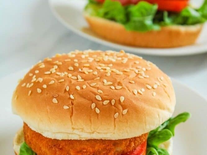 Two air fryer chicken patty sandwiches with lettuce and tomato on a white plate