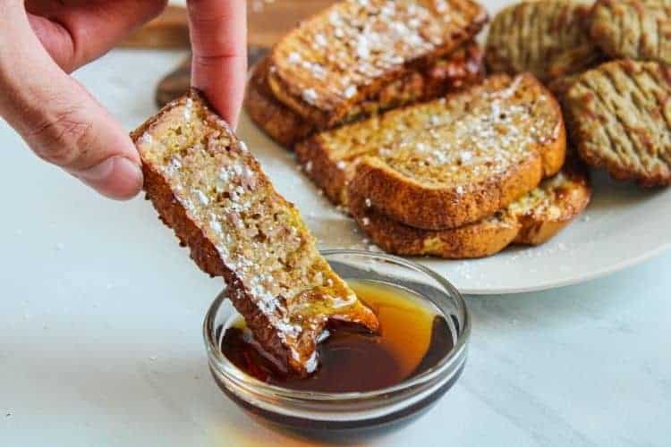 Air Fryr French Toast Stick being dipped into maple syrup