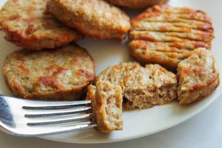 Air Fryer Sausage Patties on a white plate with one cut in half with a piece on a fork