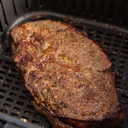 Closeup of cooked frozen steak in air fryer basket