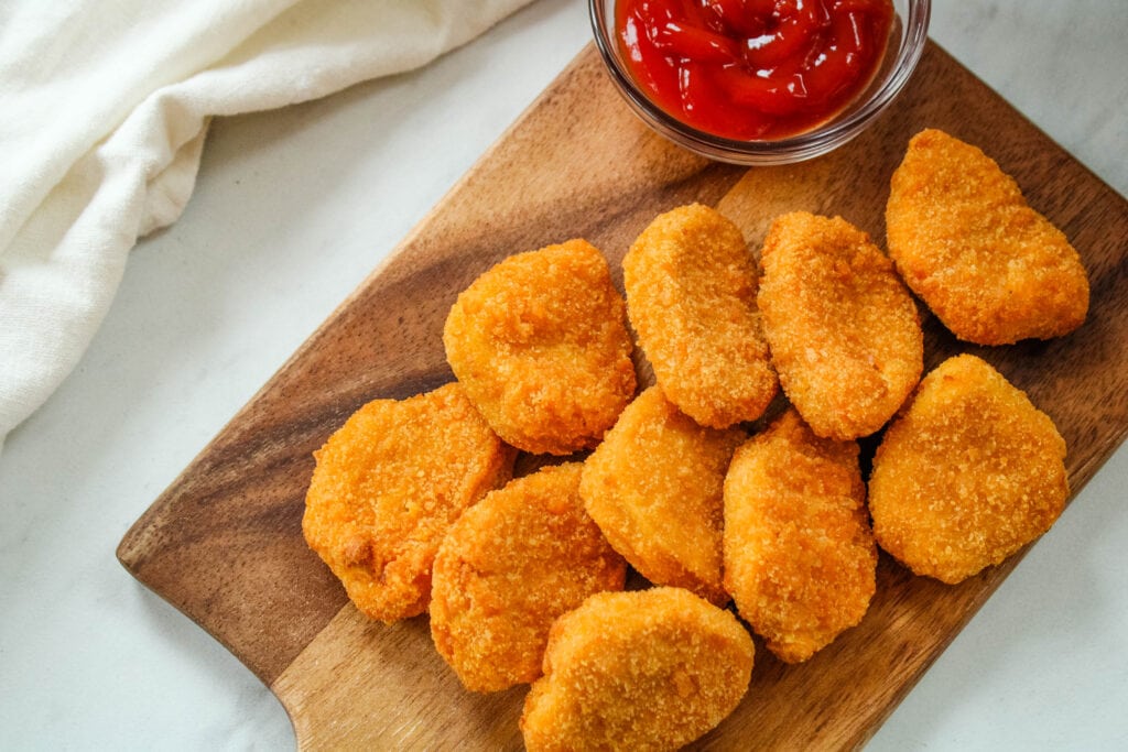 Chicken Nuggets made in the air fryer on a brown cutting board with ketchup from overhead