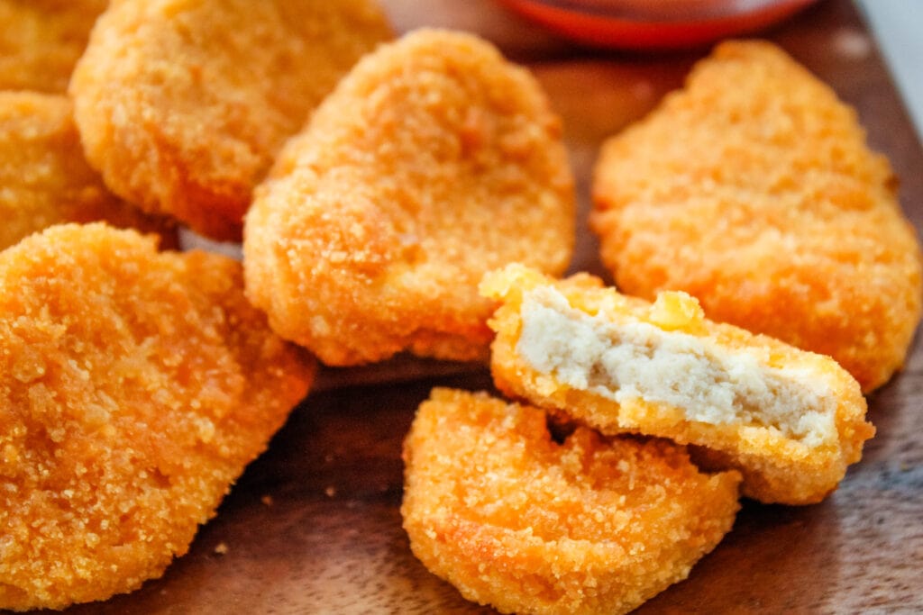 Air Fryer Chicken Nuggets on a cutting board with one bitten into