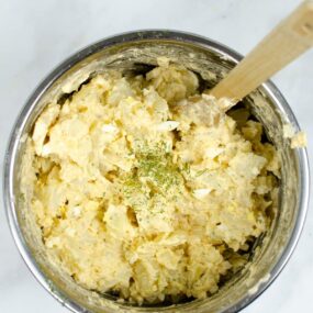 Finished potato salad inside Instant Pot with wooden spoon