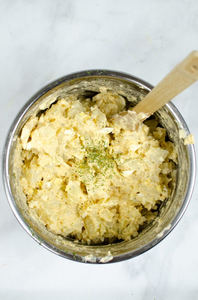 Finished potato salad inside Instant Pot with wooden spoon