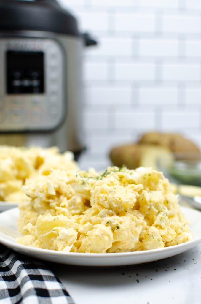 Instant Pot potato salad from side angel on a white plate with Instant Pot in background