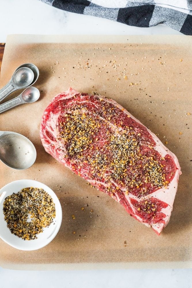 Raw Steak with seasoning on top with ingredients to side