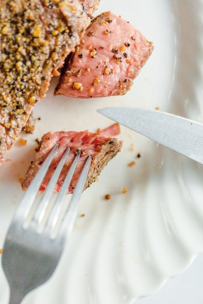 Frozen Air Fryer Steak cooked and cut into a bite-sized piece on a white plate