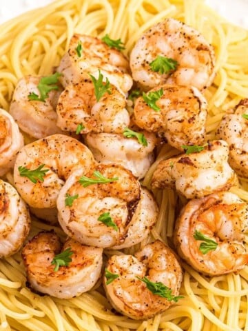 Air Fryer Shrimp on top of spaghetti on a white plate