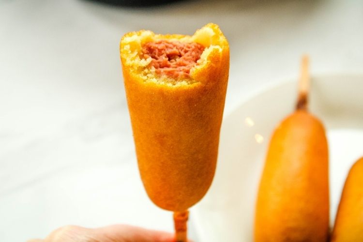 Air Fryer Corn Dog in hand with bite taken out
