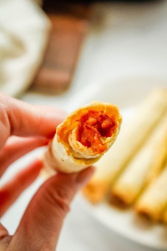 Air Fryer Taquito being held in a hand with bite taken out of it