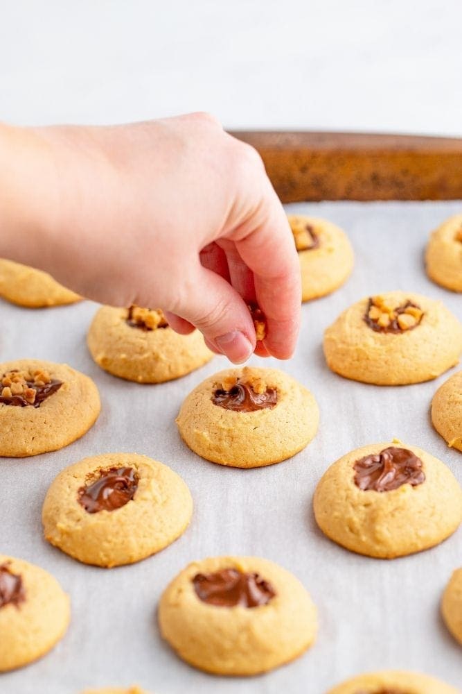 Toffee bits being placed in the middle of the chocolate toffee cookies