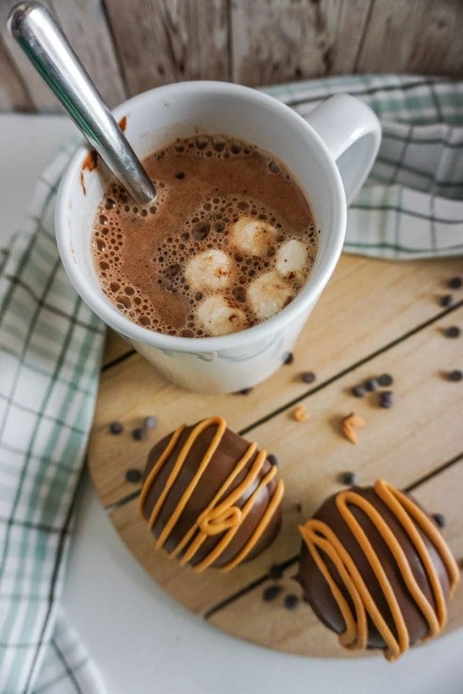 Hot Cocoa Balls with peanut butter with mug in background with exploded ball inside