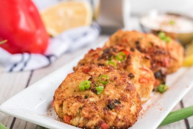Air Fryer Crab Cakes spread on a white plate with green garnish on top