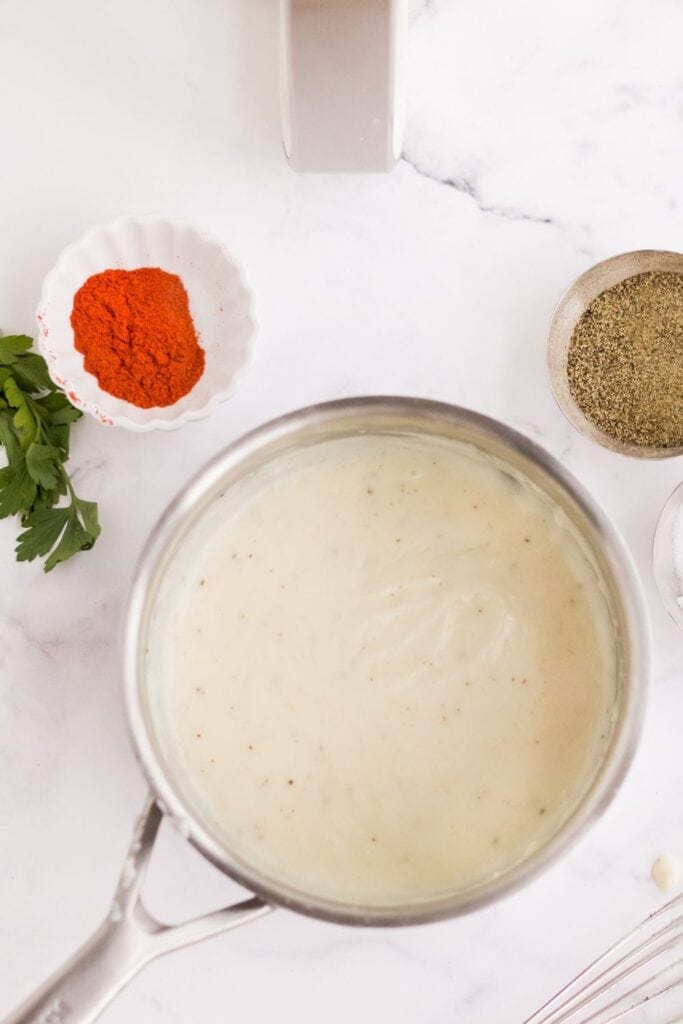 Cooked gravy in a stainless steel pot with ingredients next to it