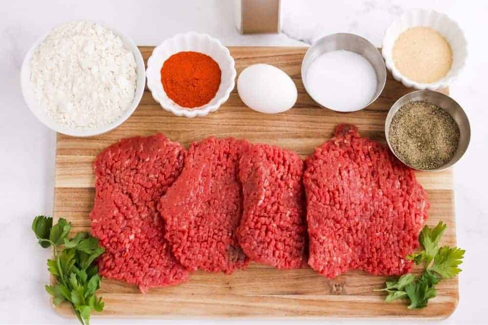 Picture of ingredients in bowls and raw cube steak on a cutting board