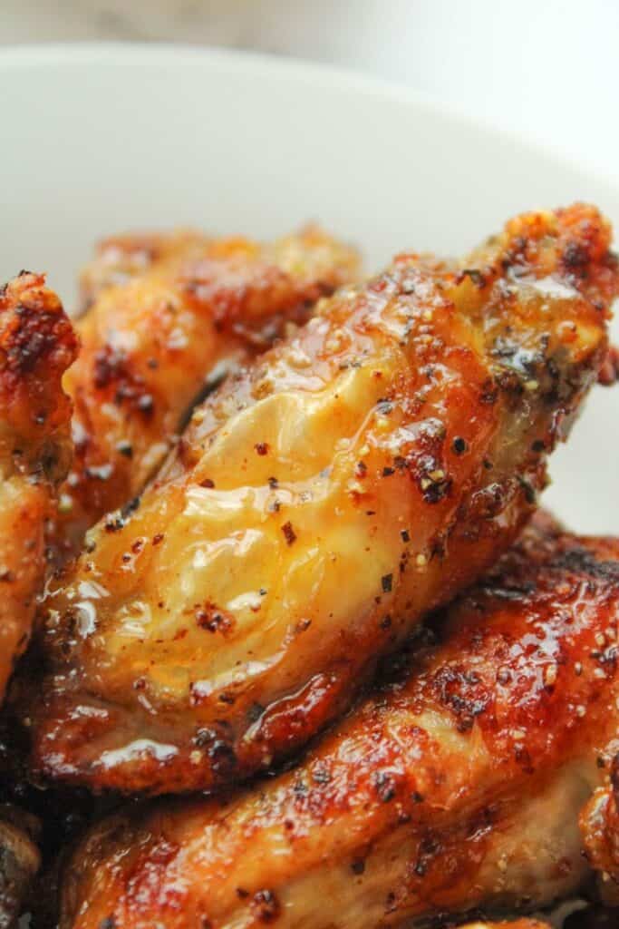 Closeup of lemon pepper chicken wing with honey wet sauce drizzled on top