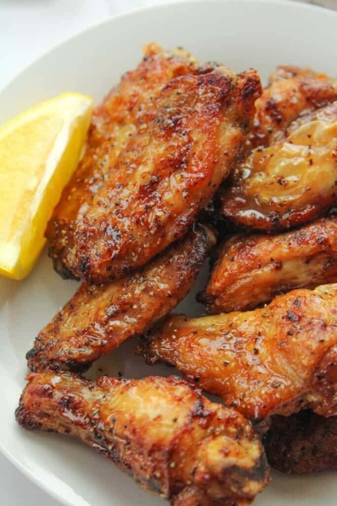 Air Fryer Lemon Pepper Wings on a white plate with a lemon slice