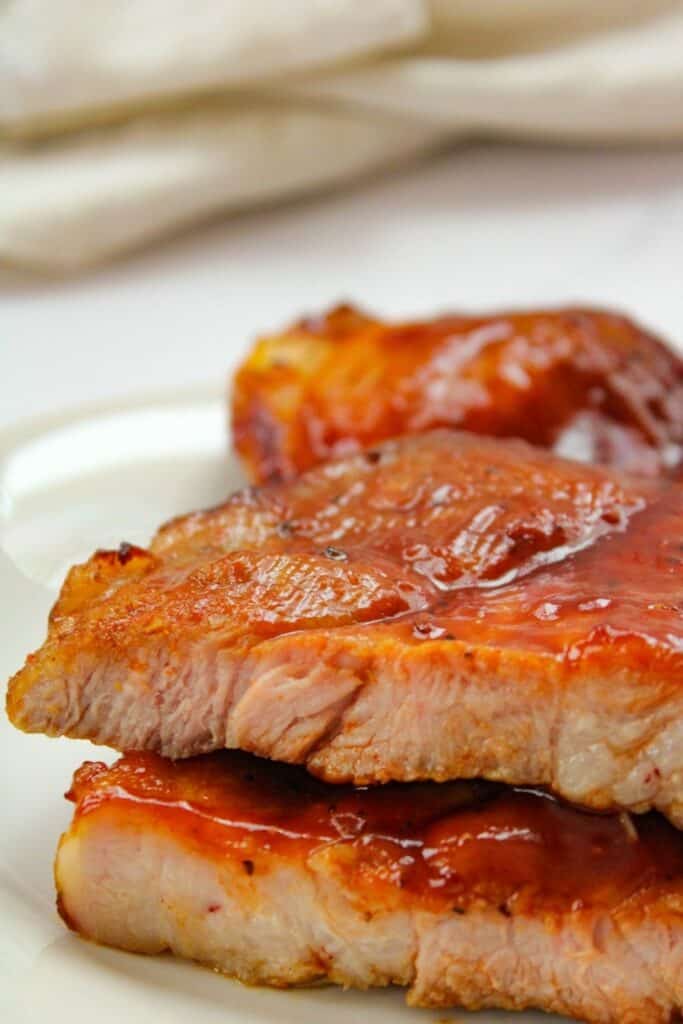 Air Fryer Pork Butt Steaks with BBQ sauce on a white plate cut open